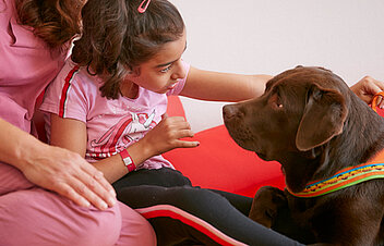 Picture: With the support of his therapist, a patient makes contact with a therapy dog by petting it.