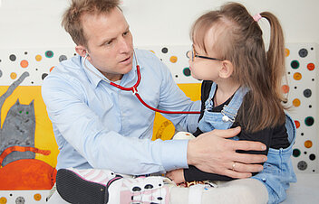 Picture: Doctor examining a child. The picture is linked to the page Overview of medical foci